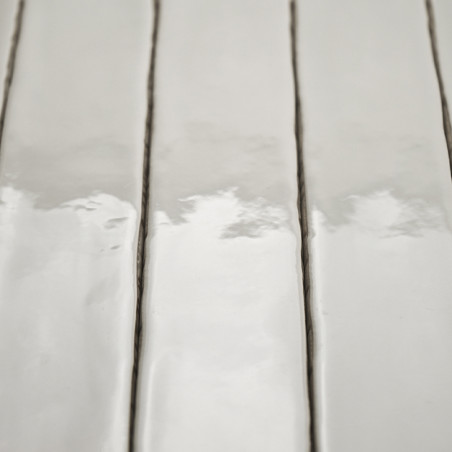 Ladrilhos cerâmicos retangulares brilhantes refletem a luz, dispostos verticalmente com linhas estreitas de argamassa escura, cr