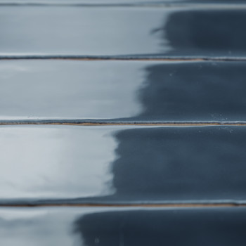 Des carreaux brillants, rectangulaires et bleu foncé sont disposés en rangées parallèles, réfléchissant subtilement la lumière. 