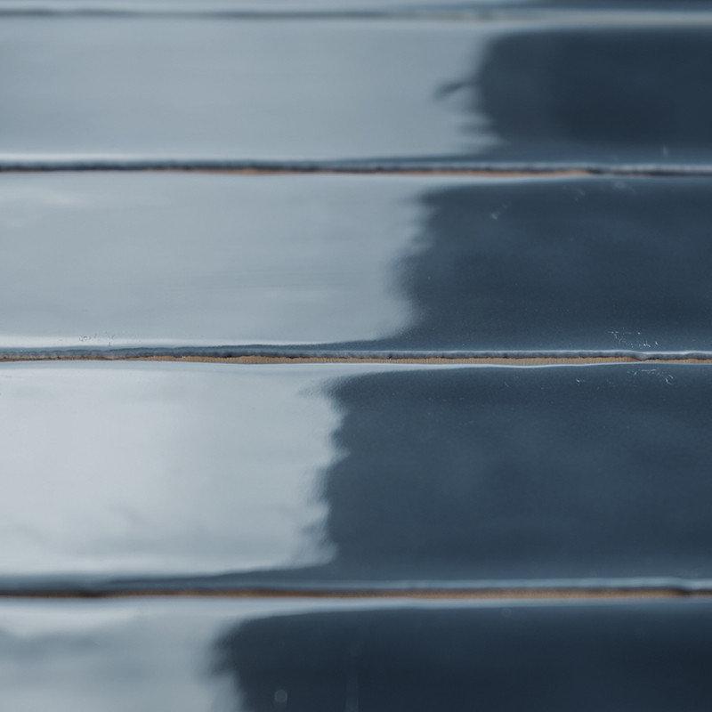 Des carreaux brillants, rectangulaires et bleu foncé sont disposés en rangées parallèles, réfléchissant subtilement la lumière. 