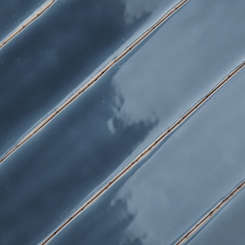 As telhas cerâmicas são posicionadas na diagonal, exibindo uma superfície brilhante e reflexiva em um gradiente de tons de azul 