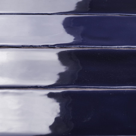 Los azulejos brillantes de color azul marino, alineados horizontalmente, reflejan la luz y las sombras en su superficie formando Los azulejos brillantes de color azul marino, alineados horizontalmente, reflejan la luz y las sombras en su superficie formando