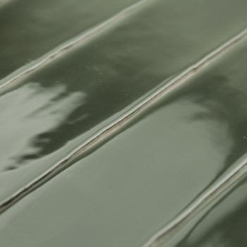 Glänzende grüne Keramikfliese mit erhabenem, geripptem Muster und dezenten Reflexen. Die Fliese wird flach verlegt und zeigt ein