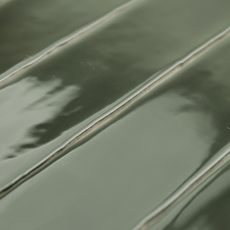 Glänzende grüne Keramikfliese mit erhabenem, geripptem Muster und dezenten Reflexen. Die Fliese wird flach verlegt und zeigt ein