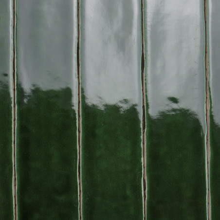Glänzende grüne Fliesen, vertikal ausgerichtet, reflektieren das Licht in einem glatten, kontinuierlichen Muster vor einem neutr