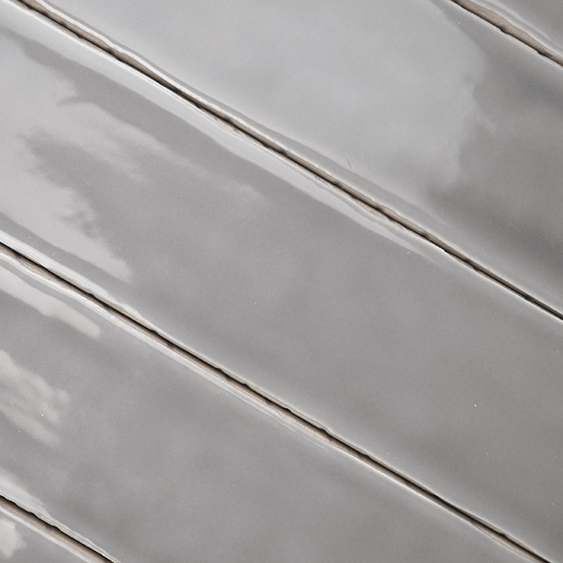 Gray ceramic tiles are arranged diagonally, reflecting light with a glossy finish, aligned closely with thin grout lines in betw