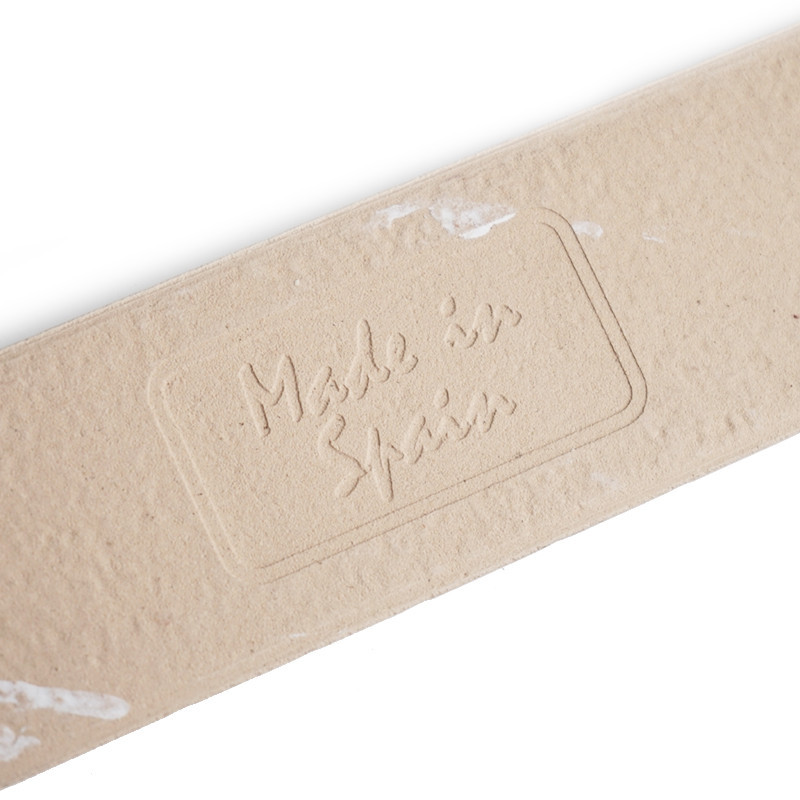 A beige tile displays embossed text, `Made in Spain,` set within a rectangular boundary, with slight white marks scattered on it