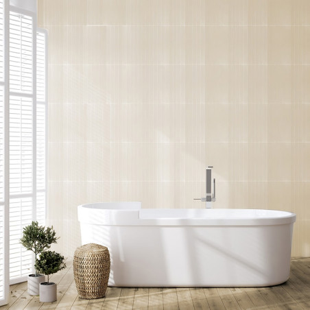 Centraal tegen beige wandtegels staat een wit bad, omgeven door houten vloeren. In de buurt zorgen een rieten mand en potplanten