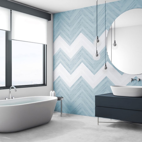 In der Nähe eines großen Fensters steht eine freistehende Badewanne. Sanfte blaue und weiße Chevron-Fliesen schmücken die Wand n