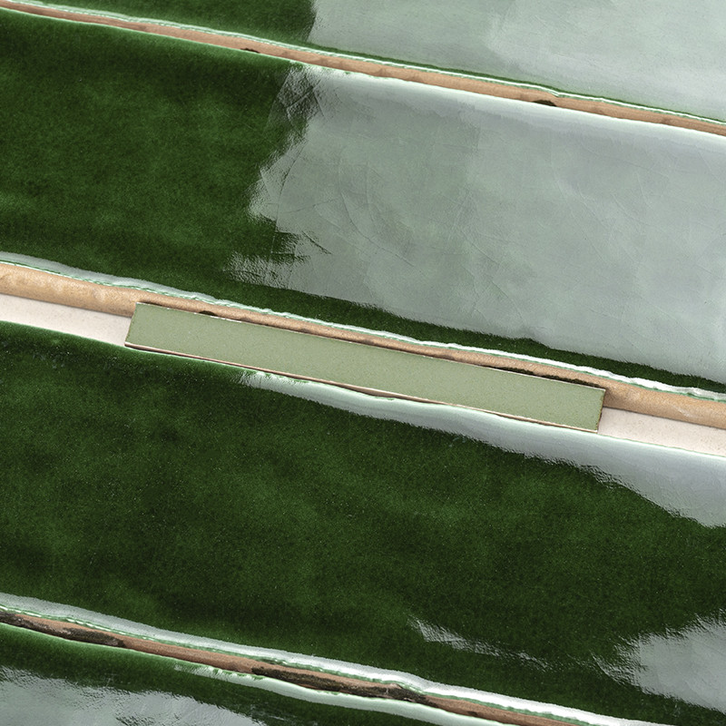 Glänzende, längliche grüne Fliesen liegen horizontal mit glatten, reflektierenden Oberflächen, getrennt durch dünne beige Fugenl