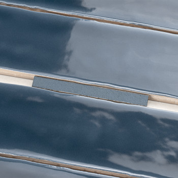 Les carreaux de céramique bleu foncé brillants aux bords biseautés sont parfaitement alignés. Des lignes de coulis séparent les 