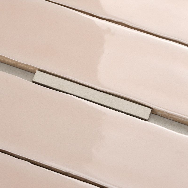 Los azulejos beige rectangulares brillantes se alinean con espacios estrechos, creando una superficie elegante. Un pequeño espac