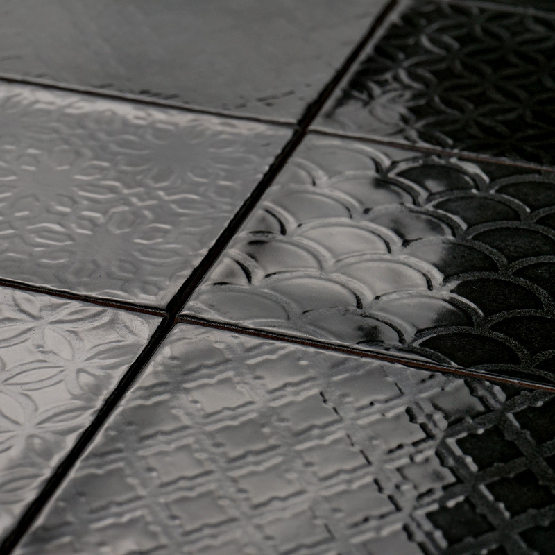 Les carreaux de céramique brillants affichent des motifs géométriques, notamment des cercles et des croix, créant une surface te