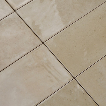 Les carreaux de céramique de couleur crème forment une grille réfléchissant doucement la lumière sur leurs surfaces brillantes. 