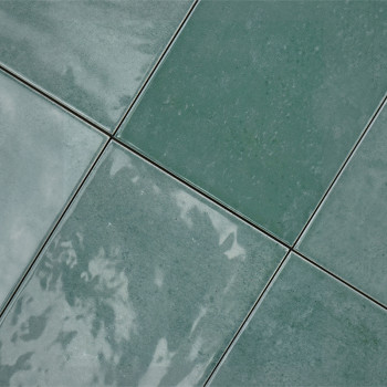 Grüne Keramikfliesen sind in einem Gittermuster angeordnet, reflektieren das Licht und weisen subtile Farbvariationen auf, wodur