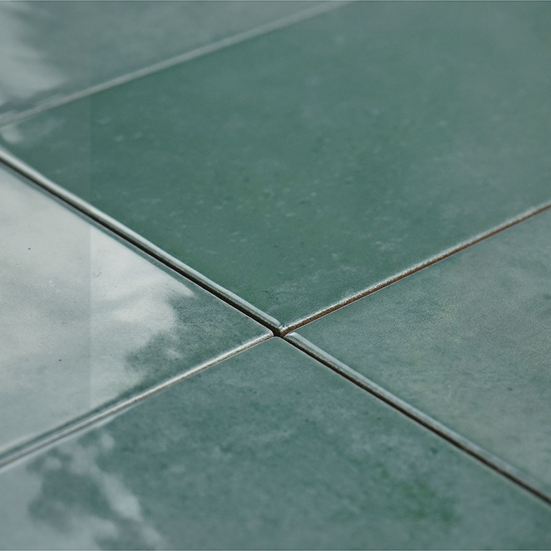In der Mitte treffen sich vier glänzend grüne Fliesen, die das Licht reflektieren und so im Innenbereich eine glatte, polierte O
