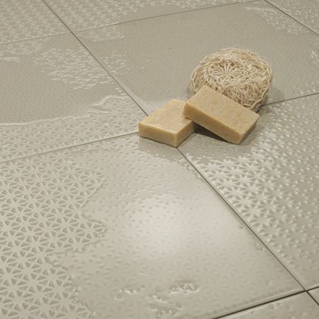 Glänzende beige Fliesen mit aufwendig geprägten Mustern sind aneinandergesetzt und halten auf ihrer glatten Oberfläche eine Luff