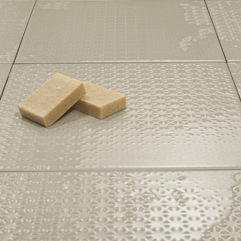 Les carreaux à texture neutre sont plats et reflètent subtilement la lumière. Deux savons rectangulaires reposent dessus, ajouta