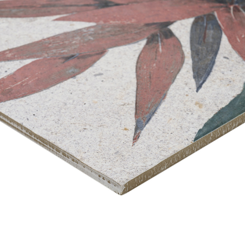 Azulejo cerámico con diseño floral con pétalos rojos y hojas verdes. colocado sobre un fondo beige moteado, mostrando sus esquin