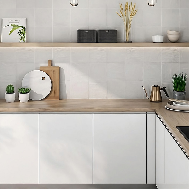Los gabinetes de cocina blancos se encuentran debajo de una encimera de madera clara, decorada con macetas y utensilios, debajo 