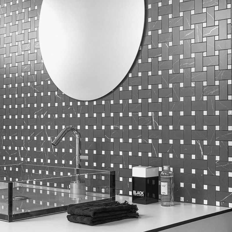 Un miroir circulaire réfléchissant est suspendu au-dessus d’un dosseret de carreaux à motifs géométriques, comportant des carrea