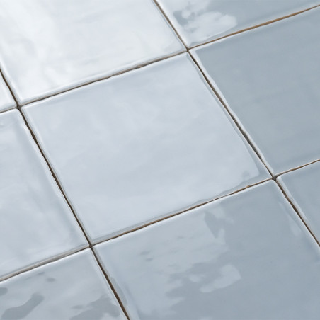 Square ceramic tiles reflecting light, arranged in a grid pattern. surface appears glossy and smooth, creating a sleek visual ef