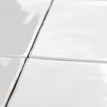 Os ladrilhos cerâmicos brancos alinham-se perfeitamente com as linhas de argamassa visíveis, refletindo a luz, criando uma super
