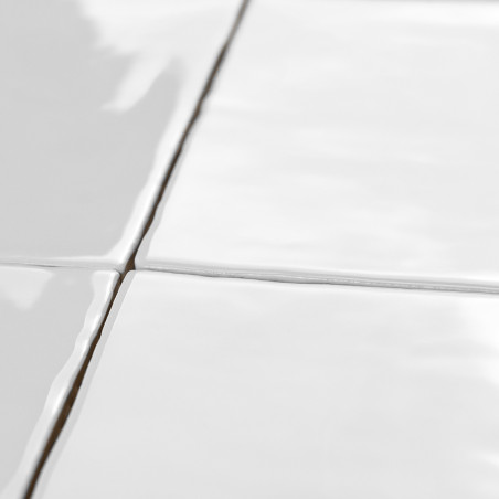Les carreaux de céramique blanche s'alignent parfaitement avec les lignes de coulis visibles, réfléchissant la lumière, créant u