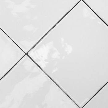 Les carreaux de céramique blanche forment un motif diagonal, avec des surfaces lisses réfléchissant la lumière, encadrées par de