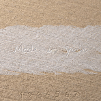 De tegel heeft de tekst `Made in Spain` en de cijfers `1 2 3 4 5 6 7` in reliëf op een beige gestructureerd oppervlak.