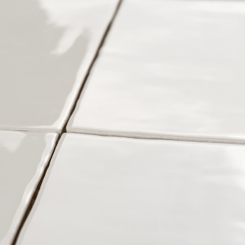 Vier glanzende, witte keramische tegels vormen een raster, verbonden door dunne voeglijnen, die het licht reflecteren in een gla