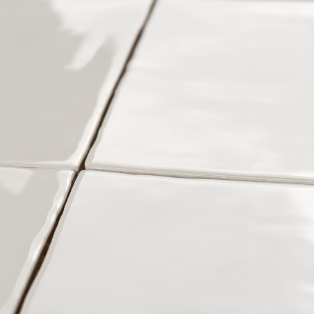 Vier glanzende, witte keramische tegels vormen een raster, verbonden door dunne voeglijnen, die het licht reflecteren in een gla