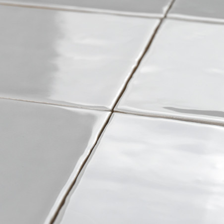 Witte keramische tegels vormen een raster met zichtbare voeglijnen, liggen plat en creëren een strak, reflecterend oppervlak in 