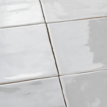 Los azulejos blancos lisos y brillantes están cuidadosamente dispuestos en forma de cuadrícula, reflejando la luz en una habitac