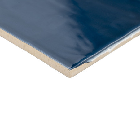 Eine rechteckige Keramikfliese weist eine glänzende, tiefblaue Oberfläche auf. Seine Kanten zeigen eine beige Unterschicht, die  Eine rechteckige Keramikfliese weist eine glänzende, tiefblaue Oberfläche auf. Seine Kanten zeigen eine beige Unterschicht, die
