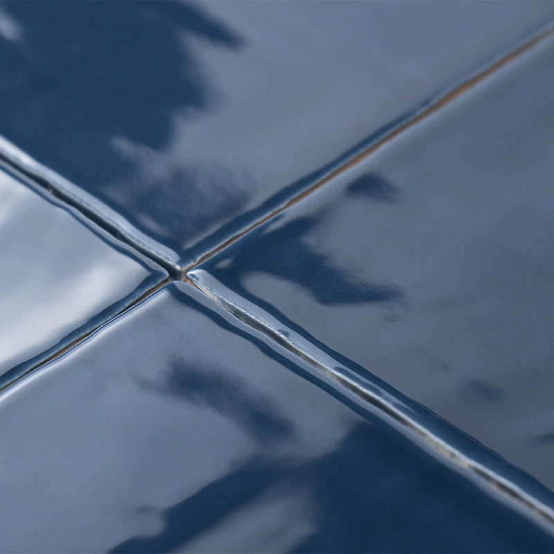Blaue Keramikfliesen mit glänzender Oberfläche reflektieren das Licht und erzeugen eine glatte, glänzende Oberfläche. Fugenlinie