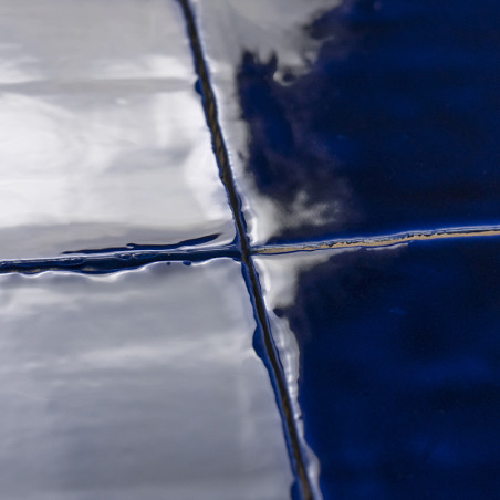 Glänzende, tiefblaue Fliesen reflektieren das Licht und kreuzen sich an sauberen Fugenlinien. Die glatte Oberfläche lässt an ein Glänzende, tiefblaue Fliesen reflektieren das Licht und kreuzen sich an sauberen Fugenlinien. Die glatte Oberfläche lässt an ein