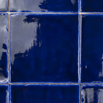 Los azulejos brillantes y de color azul intenso forman un patrón de cuadrícula. Los azulejos parecen reflectantes con ligeras va