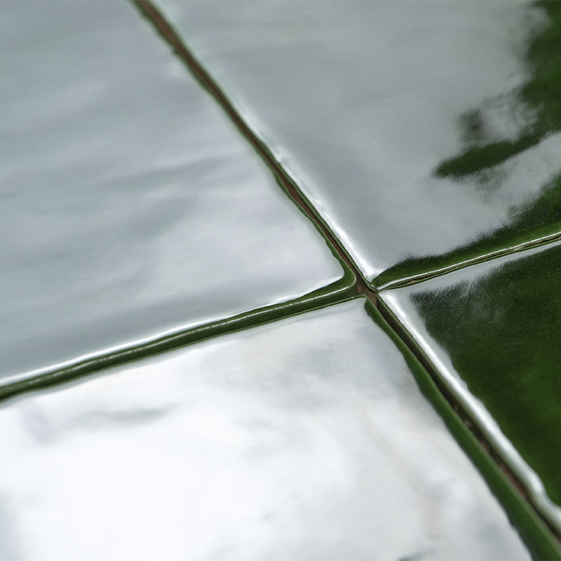 Four glossy, reflective ceramic tiles form a grid, each tile exhibiting a smooth surface, reflecting light, and featuring deep g