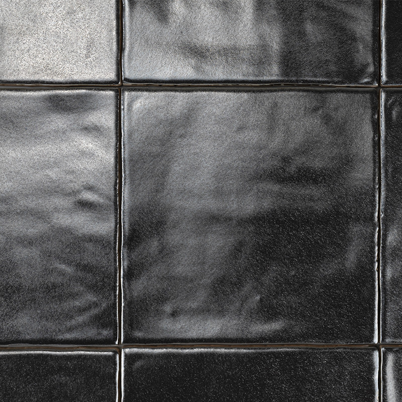 Los azulejos cuadrados de color negro brillante unidos por finas líneas de lechada crean una superficie elegante que refleja la 