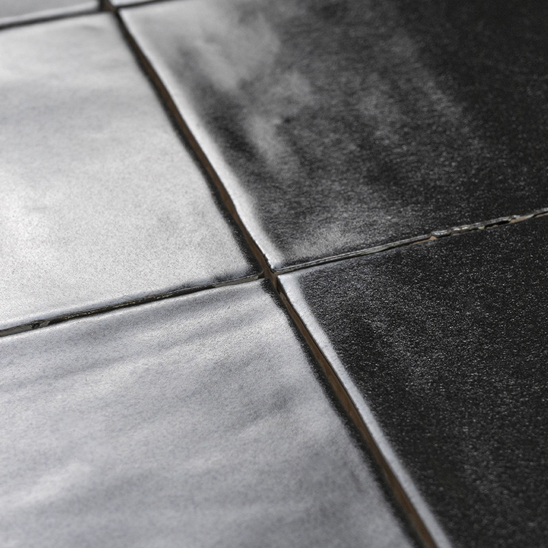 Los azulejos negros brillantes reflejan la luz, creando un brillo sutil. dispuestos en un patrón de cuadrícula con líneas de lec