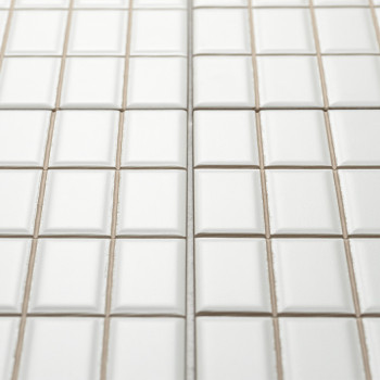 White square tiles are arranged in a grid pattern, creating a clean, uniform surface with visible grout lines in a bathroom sett