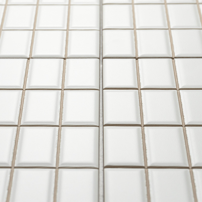 Los azulejos cuadrados blancos están dispuestos en forma de cuadrícula, creando una superficie limpia y uniforme con líneas de l