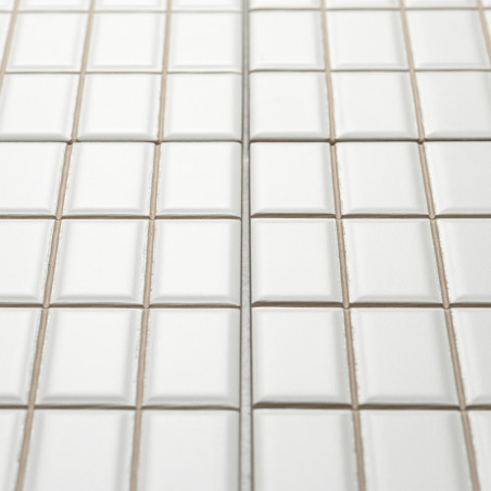 Los azulejos cuadrados blancos están dispuestos en forma de cuadrícula, creando una superficie limpia y uniforme con líneas de l