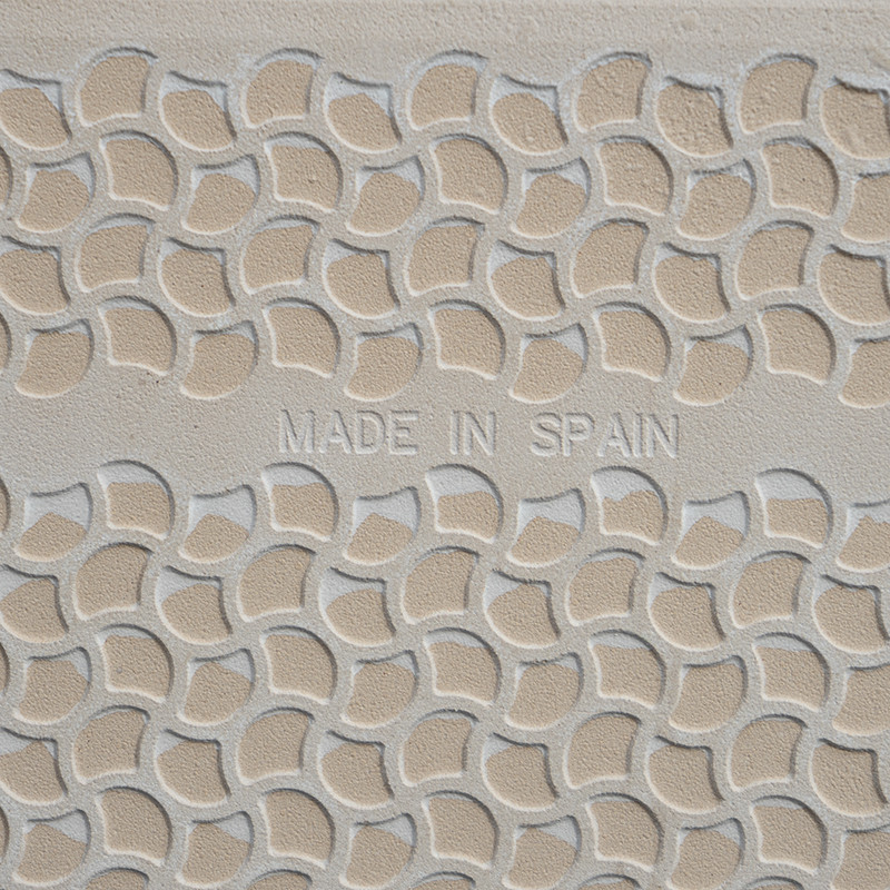 Les carreaux de céramique en relief présentent un motif d'écailles incurvées répétitives. les mots « MADE IN SPAIN » sont centré