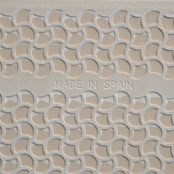 Los azulejos texturizados muestran patrones curvos superpuestos en beige y crema, con el texto `MADE IN SPAIN` grabado en el cen
