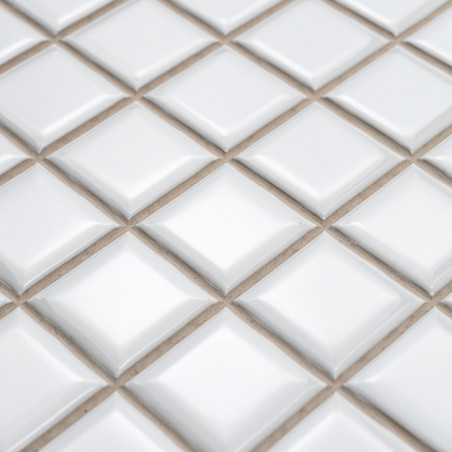 Carreaux de céramique carrés disposés en losanges avec des surfaces surélevées, créant un effet texturé et tridimensionnel sur u