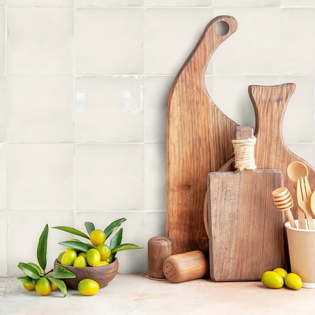 Houten snijplanken staan ​​rechtop tegen een betegelde keukenmuur, vergezeld van een schaal met groene olijven en houten keukeng