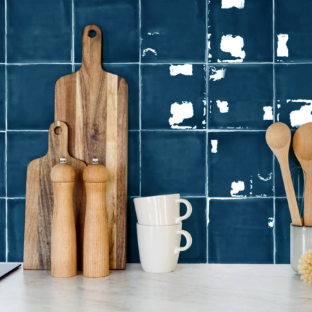 Holzschneidebretter stehen aufrecht. Davor stehen Salz- und Pfeffermühlen. Zwei gestapelte Tassen stehen in der Nähe. Blaue Kach Holzschneidebretter stehen aufrecht. Davor stehen Salz- und Pfeffermühlen. Zwei gestapelte Tassen stehen in der Nähe. Blaue Kach