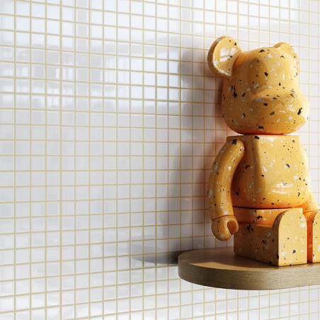 Uma figura laranja e salpicada em forma de urso está sentada em uma prateleira de madeira. Tem como fundo pequenos ladrilhos qua