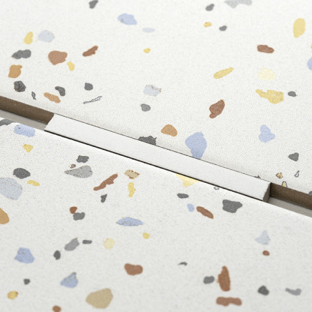 Speckled terrazzo tile, displaying scattered colorful flecks, lies adjacent to another tile with a visible straight grout line, 